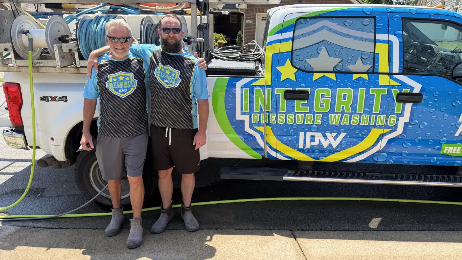 Integrity Pressure Washing crew standing beside the branded service truck.